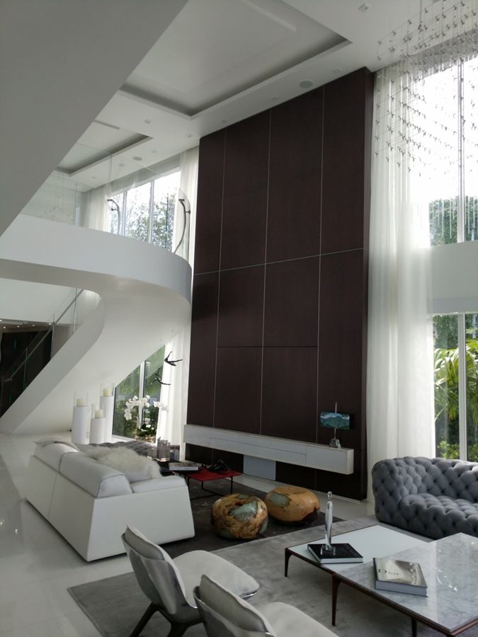 Double-height dark wood veneer feature wall with a floating TV console in a living room with a curved staircase