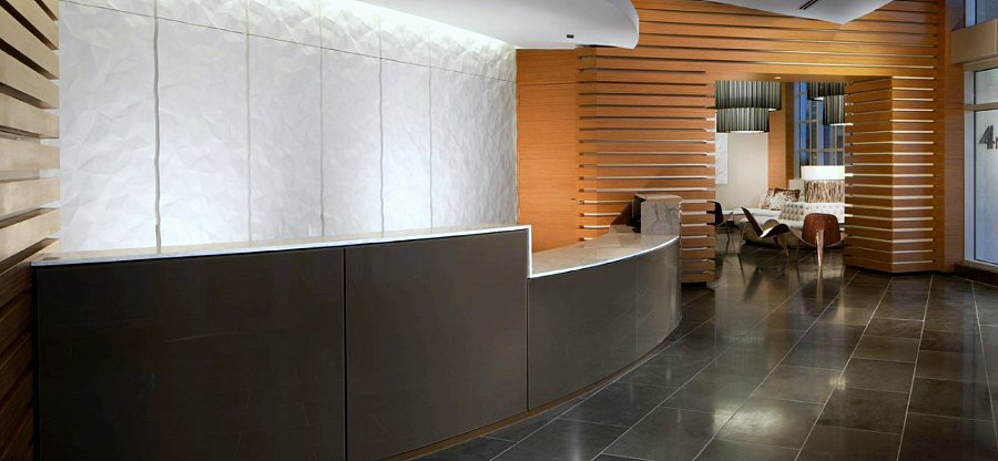 Lobby with a curved grey reception desk and wood slat panelling