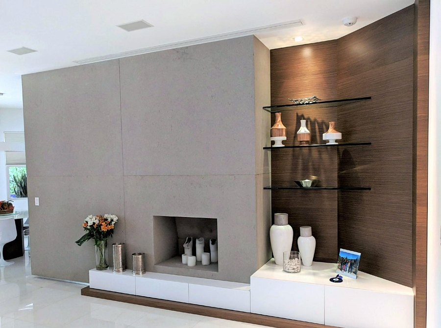 Fireplace wall with white low storage, wood panel and glass shelves