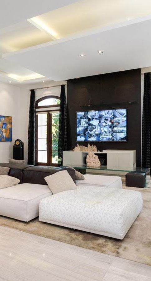 Living room with a dark floor-to-ceiling wall panel, screen and white console